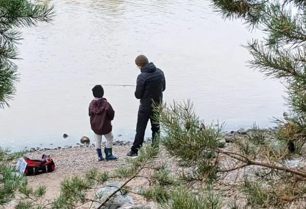 Mieskaveri ja lapset kalastavat rannalla.